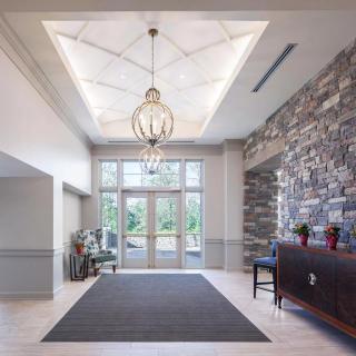 A modern lobby entrance featuring a large chandelier, stone accent wall, and glass doors allowing natural light.