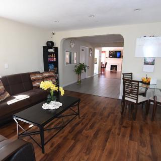 A spacious living area featuring a comfortable sofa and dining table with hardwood flooring.
