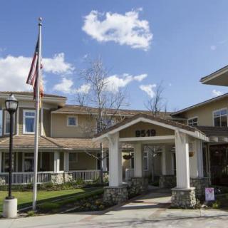 A residential building with an American flag at the entrance on a sunny day.