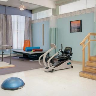 A rehabilitation exercise room with various fitness and therapy equipment.