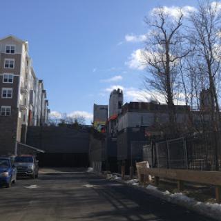 A quiet urban street with buildings lining the sides under a clear blue sky.