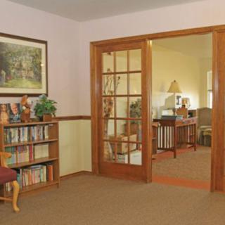 A cozy living room with a bookshelf and French doors opening to another room.