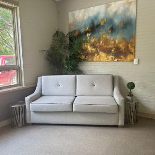 A cozy living room featuring a stylish sofa, contemporary artwork, and greenery.
