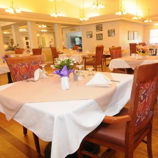 A warmly lit dining room with elegantly set tables and comfortable chairs.