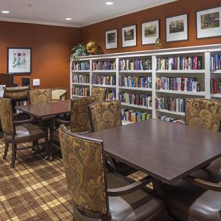 A cozy library space with bookshelves, tables, and chairs for reading.
