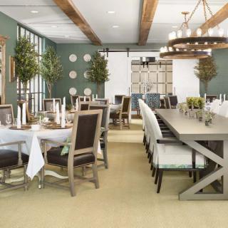 A modern dining room featuring elegant tables, chairs, and sophisticated lighting with greenery accents.