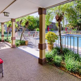 A covered patio area overlooking a pool surrounded by lush tropical plants.