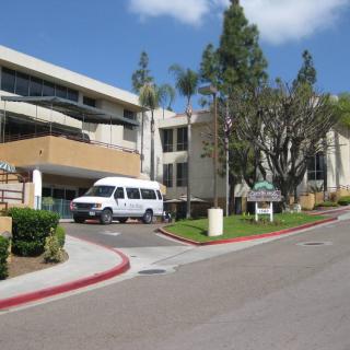 A hospital building with a van parked at the entrance.