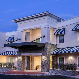 A modern hotel building with striped awnings and a welcoming entrance in the evening.