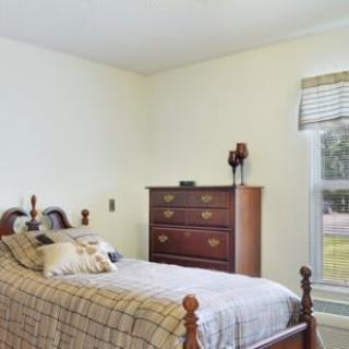 A cozy bedroom with a single bed and a dresser by the window.