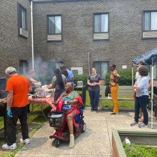 A group of people enjoying a barbecue in an outdoor area beside a building.