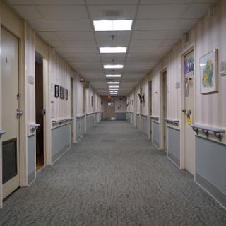 A long, well-lit corridor featuring multiple doors on both sides.