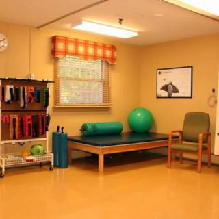 A rehabilitation room equipped with exercise tools including a therapy mat, exercise ball, and resistance bands.