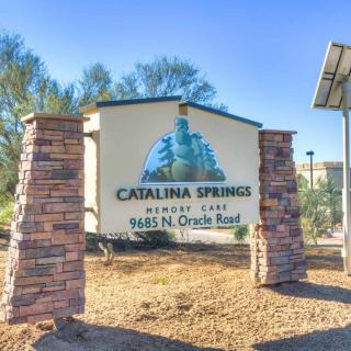 Entrance sign for Catalina Springs Memory Care with stone pillars and trees in the background.