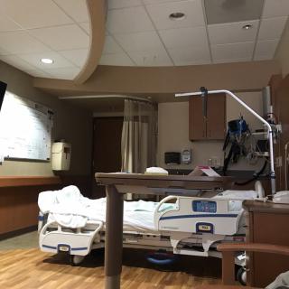 An empty hospital room with a medical bed and equipment.