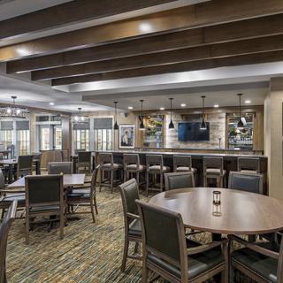 Modern dining area with tables, chairs, and a bar.