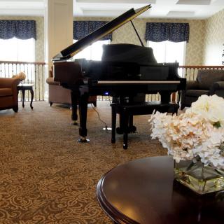A luxurious living room featuring a grand piano and elegant floral decor.