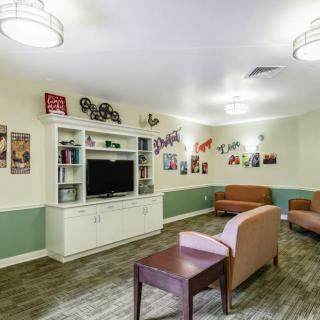 A cozy community living room with seating, a television, and decorative elements on the walls.