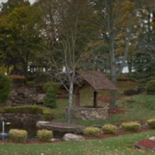 A scenic view of a garden with lush greenery and a small wooden structure.