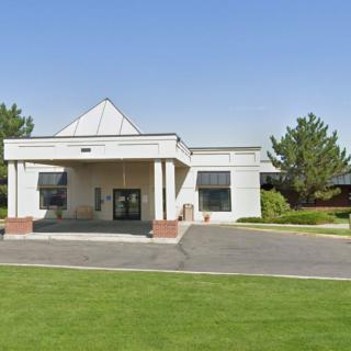 A building entrance with a well-kept lawn and clear blue sky.