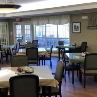 A neatly arranged dining room with multiple tables and chairs by large windows.