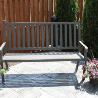 A wooden bench placed on a sunny patio next to potted plants.