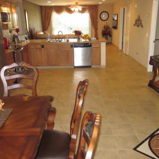 A spacious dining and kitchen area with wooden furniture and tiled flooring.