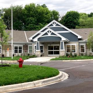 A suburban residential building with a landscaped front yard and a circular driveway.