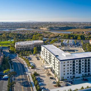 Aerial view of a modern hotel surrounded by urban landscape and green areas.