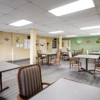 An empty dining room with neatly arranged tables and chairs under bright ceiling lights.