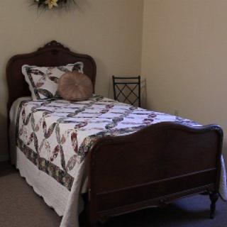 A cozy bedroom with a single bed featuring a decorative quilt and wooden headboard.