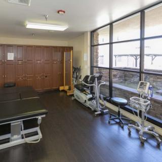A well-equipped physical therapy room with exercise machines and therapy tables.