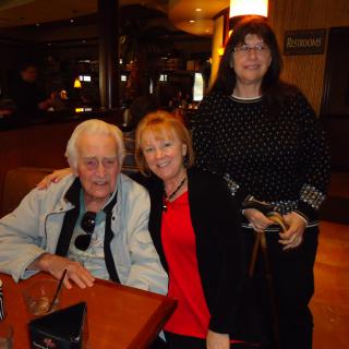 A group of three people smiling together in a restaurant setting.