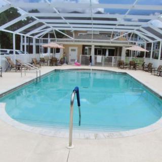 An enclosed outdoor swimming pool with surrounding patio furniture.