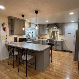 A modern kitchen with gray cabinets, an island with seating, and stainless steel appliances.