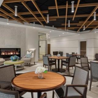 A modern lounge area featuring wooden tables, comfortable seating, and a fireplace.