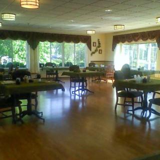 A spacious dining room with tables and chairs set up, illuminated by natural light from large windows.