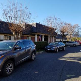 A peaceful residential street lined with parked cars and bare trees.