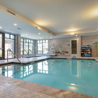 A serene indoor pool area featuring large windows and a modern aesthetic.