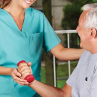 A healthcare professional assists an elderly person with a physical exercise using a dumbbell.