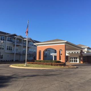 A modern building with an American flag at the entrance under a clear blue sky.