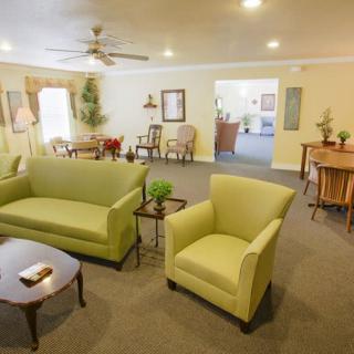 A cozy living room with green sofas and armchairs, complemented by warm lighting and tasteful decor.