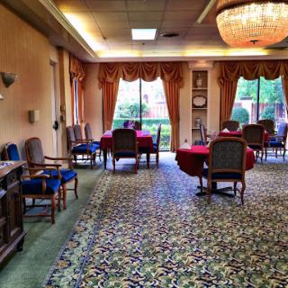 A cozy lounge area featuring a floral carpet, elegant furniture, and ample natural light.