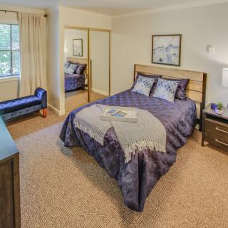 A cozy bedroom with a neatly made bed, mirror closet, and elegant decor.