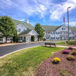 A well-maintained building with a landscaped garden and driveway under a vibrant blue sky.