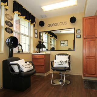 A stylish hair salon interior featuring a comfortable chair, large mirror, and wooden flooring.
