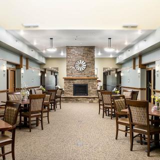 A spacious dining room with tables and chairs, featuring a central fireplace and clock.