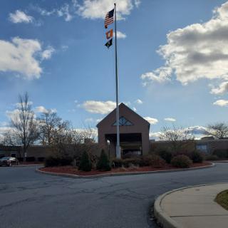 A building with flags surrounded by a landscaped area under a blue sky.