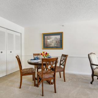 A cozy dining area with a round table, four chairs, and wall artwork.