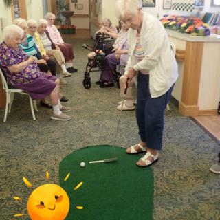 Seniors enjoying a lively indoor mini-golf session, promoting fun and fitness.